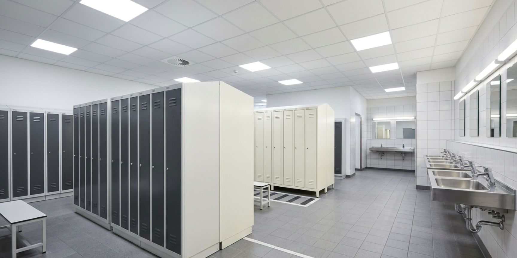 Clean changing area in the warehouse with sturdy lockers, sink row, showers, and non-slip floor for employee hygiene.